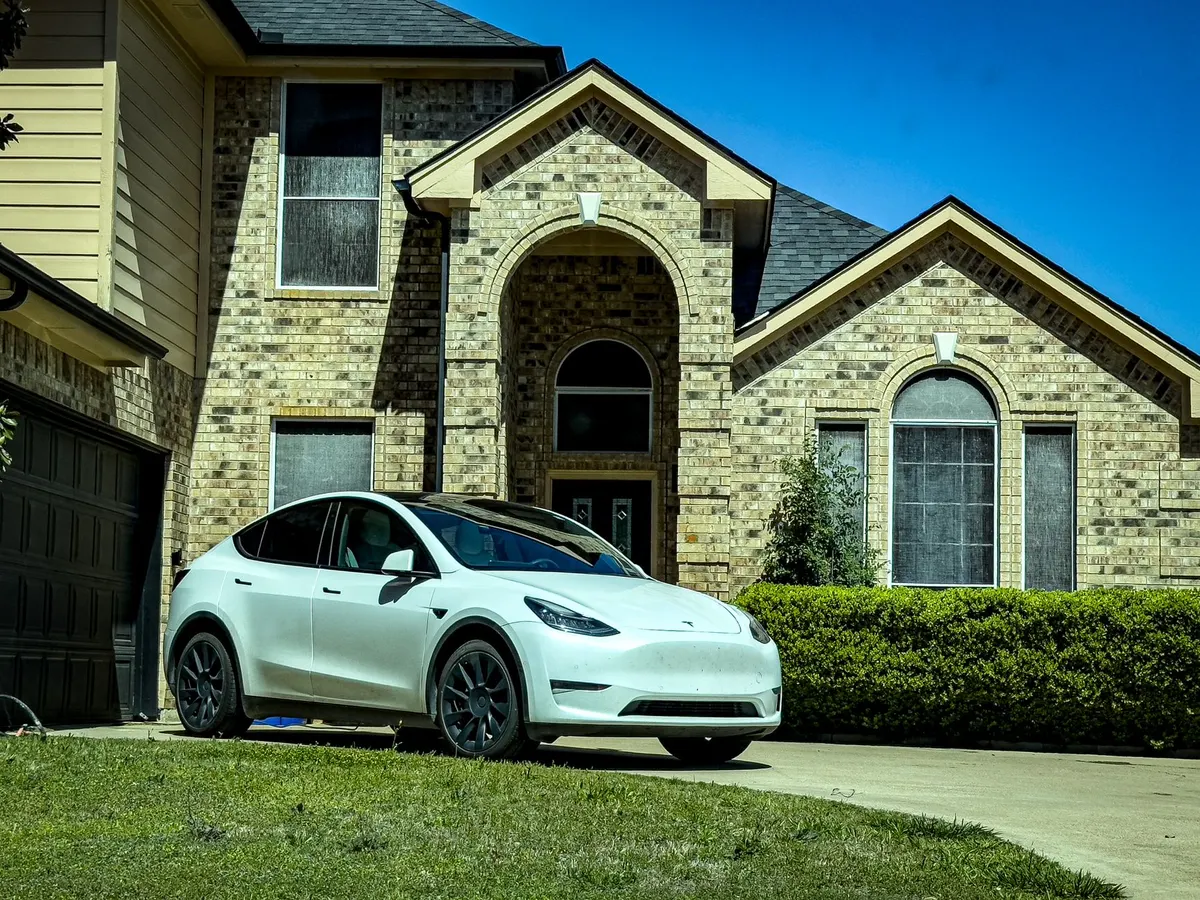 Voiture électrique stationnée devant une maison, prête pour l'installation d'une borne